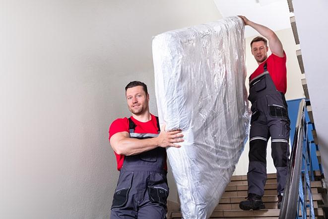 home renovation team hauling away an old box spring in Berlin